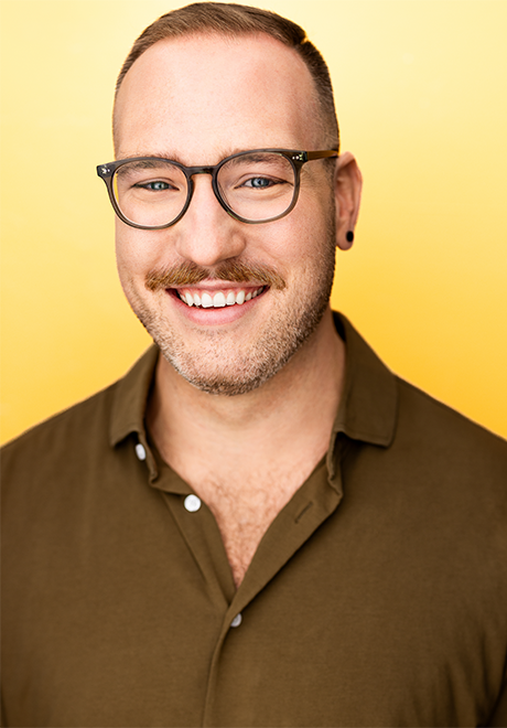 Craig Juricka headshot; smiling in a brown shirt with a yellow background