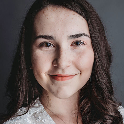 Sophia Ross Alvarez headshot: smiling in white shirt in front of gray background