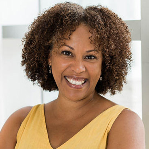 Krisha Marcano smiling; she is wearing a yellow dress in front of a white background