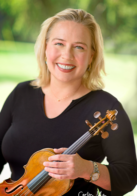 Caroline Pliszka smiling while holding violin in black shirt.