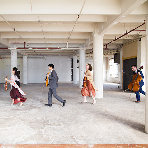 four musicians run across a room 