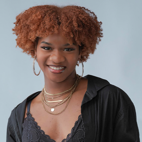 Ololade Robinson headshot, smiling in front of a light blue wall