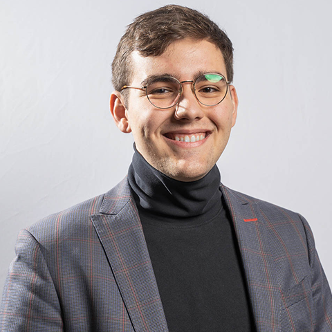 Andrei Radu headshot: wearing a grey jacket and black turtleneck shirt.