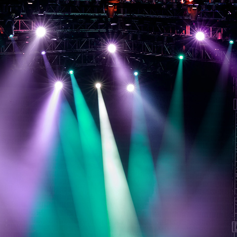 Stage lights in green and purple shine down.