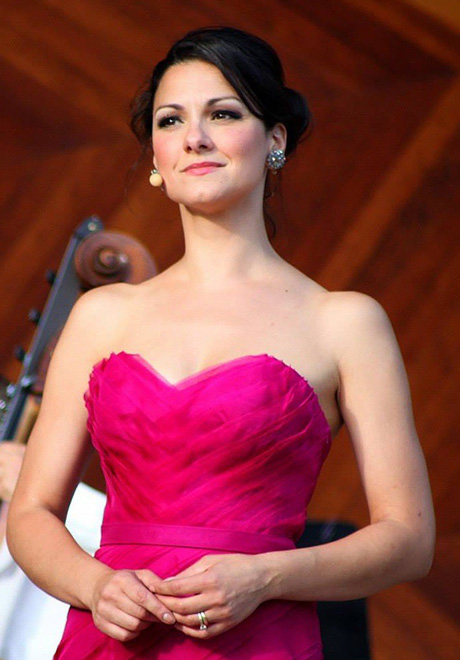 Sanra Piques Eddy headshot: smiling and wearing a bright pink strapless formal gown.