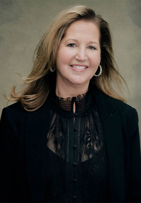 Noel Smith headshot: smiling in all black clothes in front of a gray background.