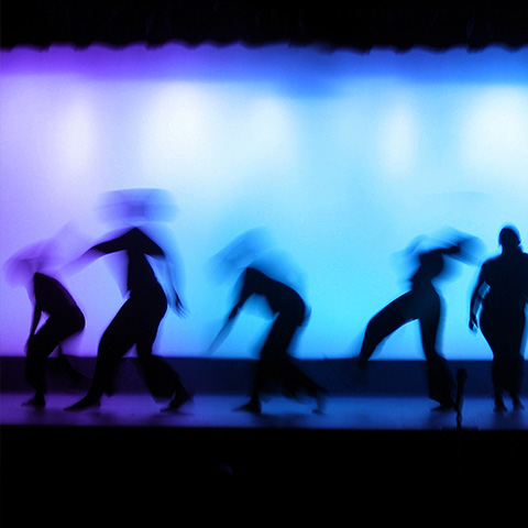 a group of dancers in front of a blue and purple background
