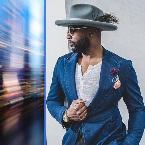 Norman Garrett headshot, in blue suit and hat, looking to the left