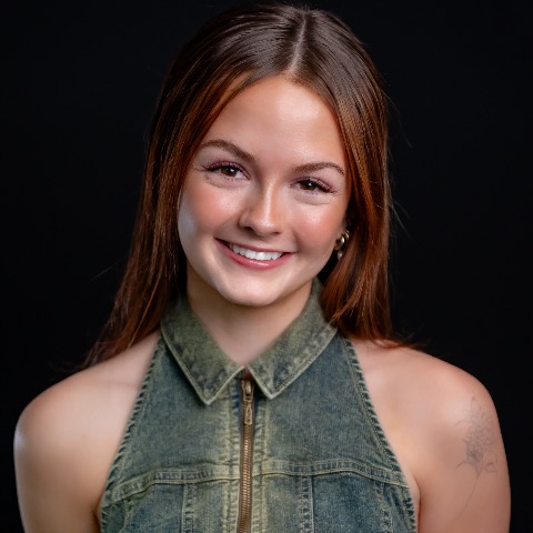 Kate Farmer headshot: wearing a denim top in front of a black background