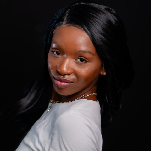 Bini Marshall headshot: face facing forward with body angled to the left in a white shirt. Image has a black background.
