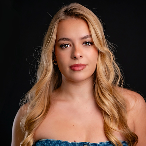 Emily Vincent headshot: wearing a strapless denim top in front of a black background