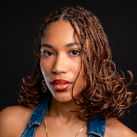 Honor Minors headshot: wearing a denim top in front of a black background.