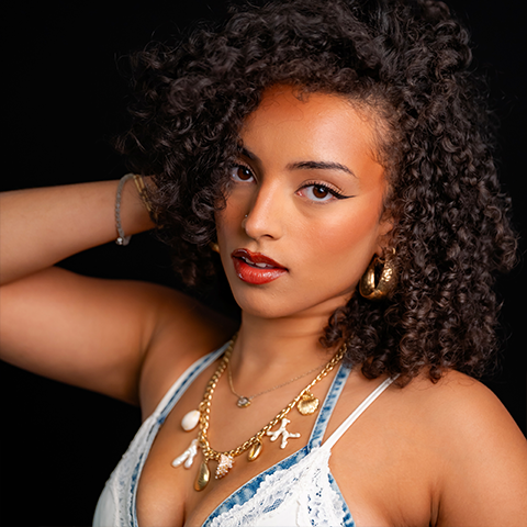 Lindsay Williams headshot: wearing a white and denim tank top in front of a black background