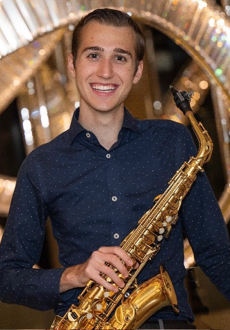Xander Dawson headshot: smiling and holding a saxophone