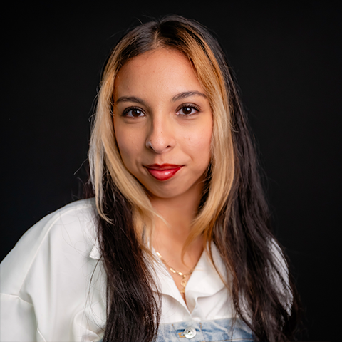 Dalila Sanchez headshot: wearing a white and denim shirt in front of a black background