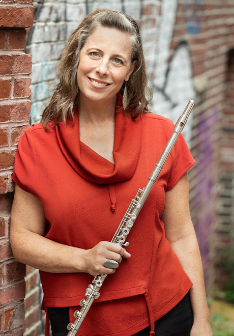 Sarah Brady headshot: wearing a red/orange shirt and holding her flute