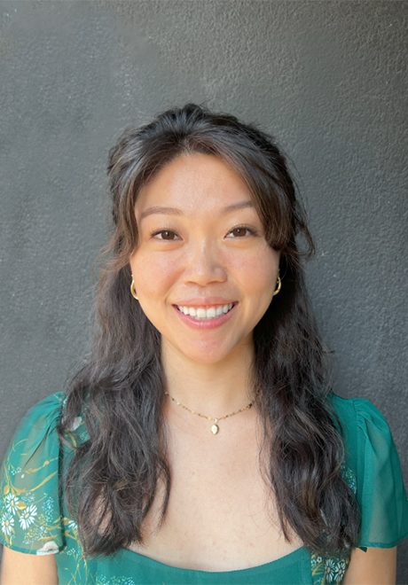 Moriah Tom headshot: smiling in teal shirt in front of a gray background