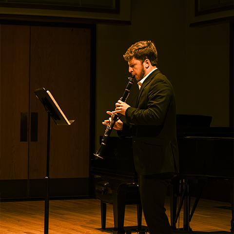 Nathan Soric in a suit playing the clarinet 