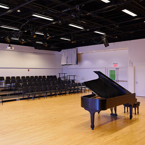 Studio 401, room with wooden floors, a piano, and a set of chairs in the audience section