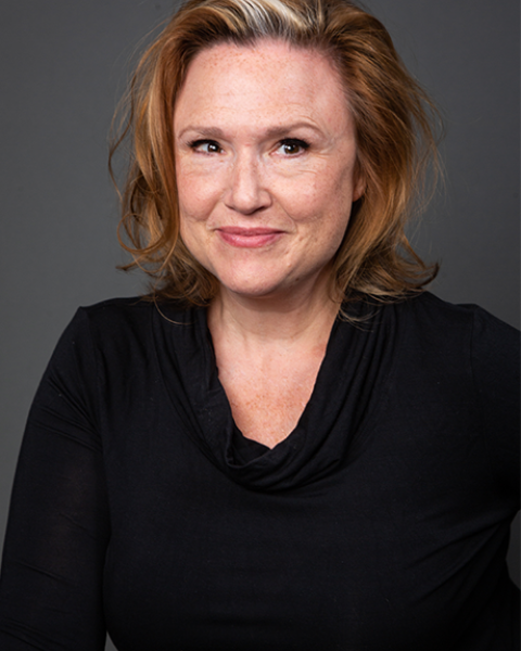 Jennie Israel headshot: smiling and wearing a v-cut long sleeve black top.