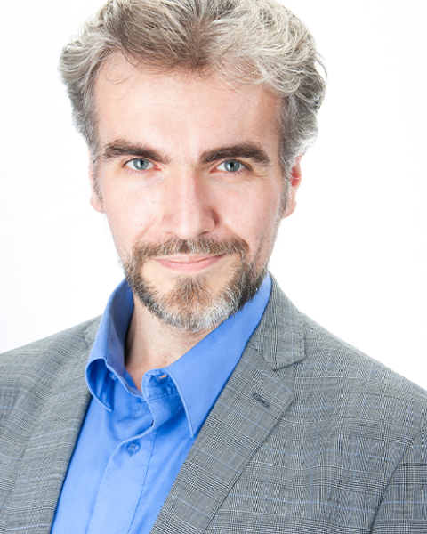 Alexandr Polyakov headshot: in gray suit and blue shirt