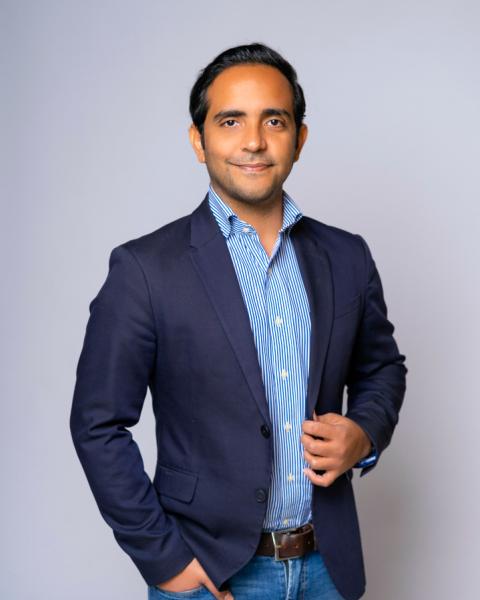 Carlos Vargas headshot, smiling. Carlos is wearing jeans with a shirt and jacket.