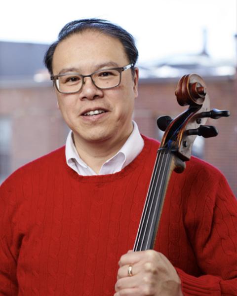 Andrew Mark headshot; holding cello and wearing red sweater.