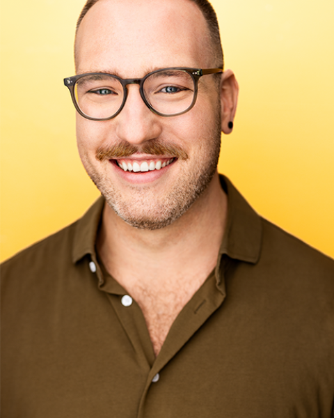 Craig Juricka headshot; smiling in a brown shirt with a yellow background
