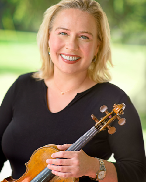 Caroline Pliszka smiling while holding violin in black shirt.