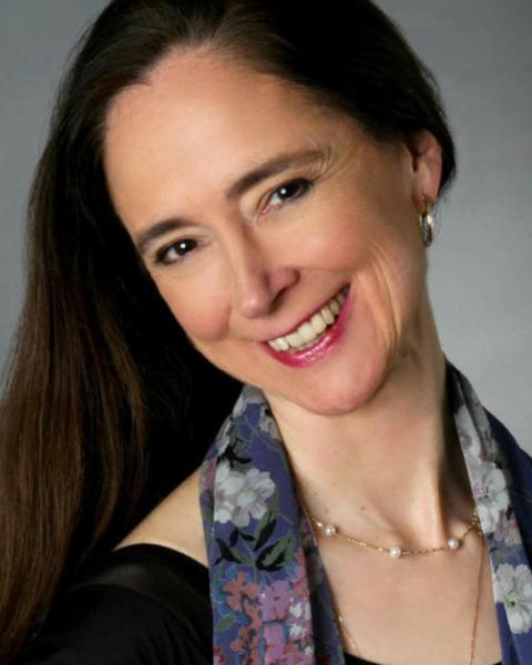 Anne Higgins headshot: smiling and wearing a scarf and black shirt