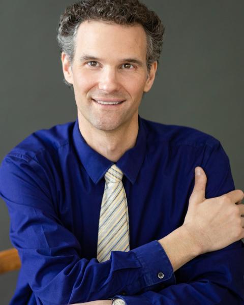 Gregory Zavracky headshot, wearing a deep blue shirt with a white/gray tie.