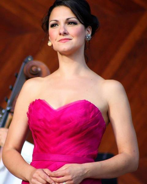 Sanra Piques Eddy headshot: smiling and wearing a bright pink strapless formal gown.