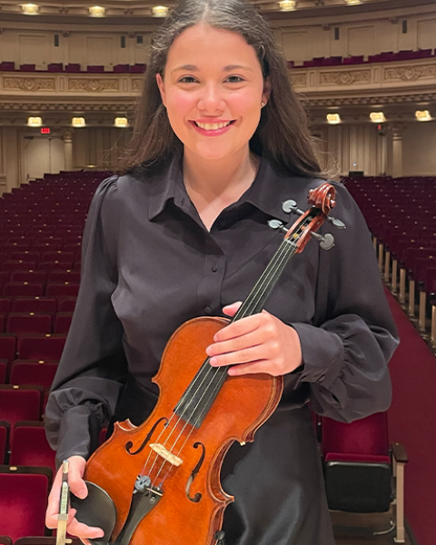 Acadia Kunkel headshot: smiling in all black clothes holding a violin