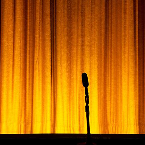 A stage curtain closed, with a microphone silhouette 