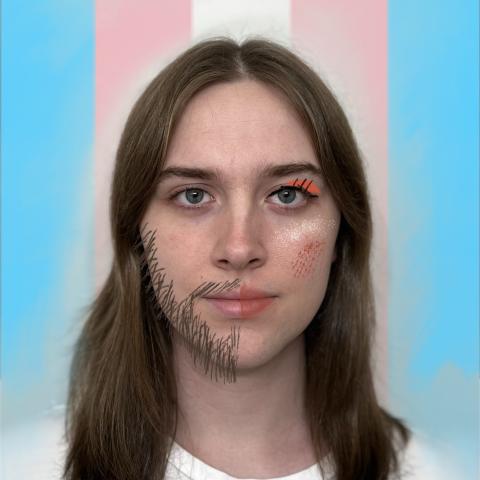 Sam Crosby-Schmidt in front of the trans flag colors (blue, pink, and white) with half of face with drawn on facial hair and other half of face with drawn on makeup