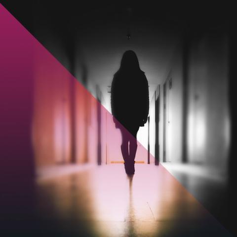 Black and white picture of a silhouette person in a school hallway with a pink hue on the left side 