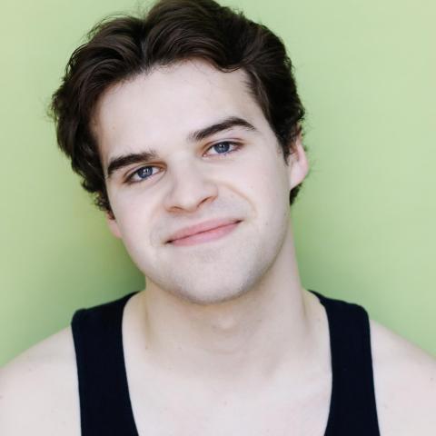 Nathanael Walsh headshot: smiling in black tank top with light green background