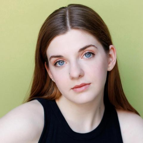 Bella West headshot: posing in black shirt with light-green background