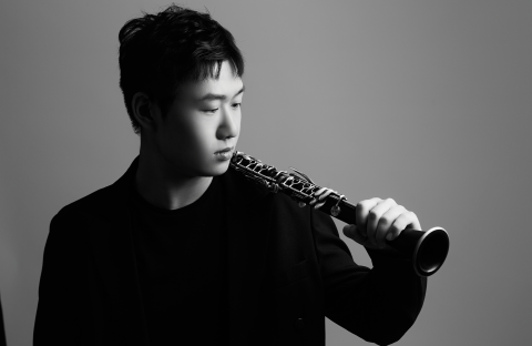 Chenglin Yang posing with his clarinet in a black and white photo