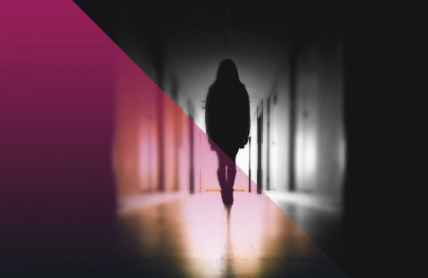 Black and white picture of a silhouette person in a school hallway with a pink hue on the left side 