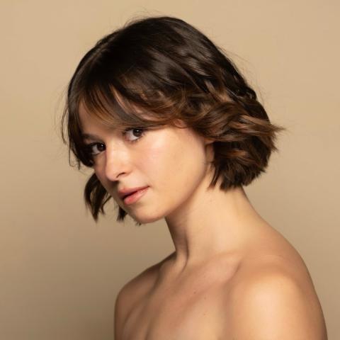 Brooke Zide headshot: posing in front of a tan wall