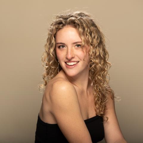 Chloé Wasser headshot: smiling over shoulder with black tube top