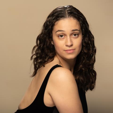 Gabrielle Honoré headshot: posing in a black tank top looking over her shoulder