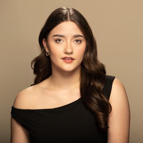 Tess O'Riordan headshot: posing with a black off-the-shoulder top