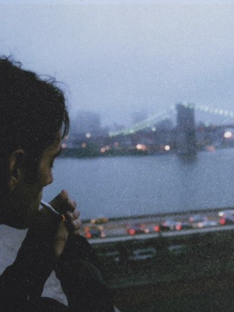Silhouette of guy smoking as he looks at a road and river across from him